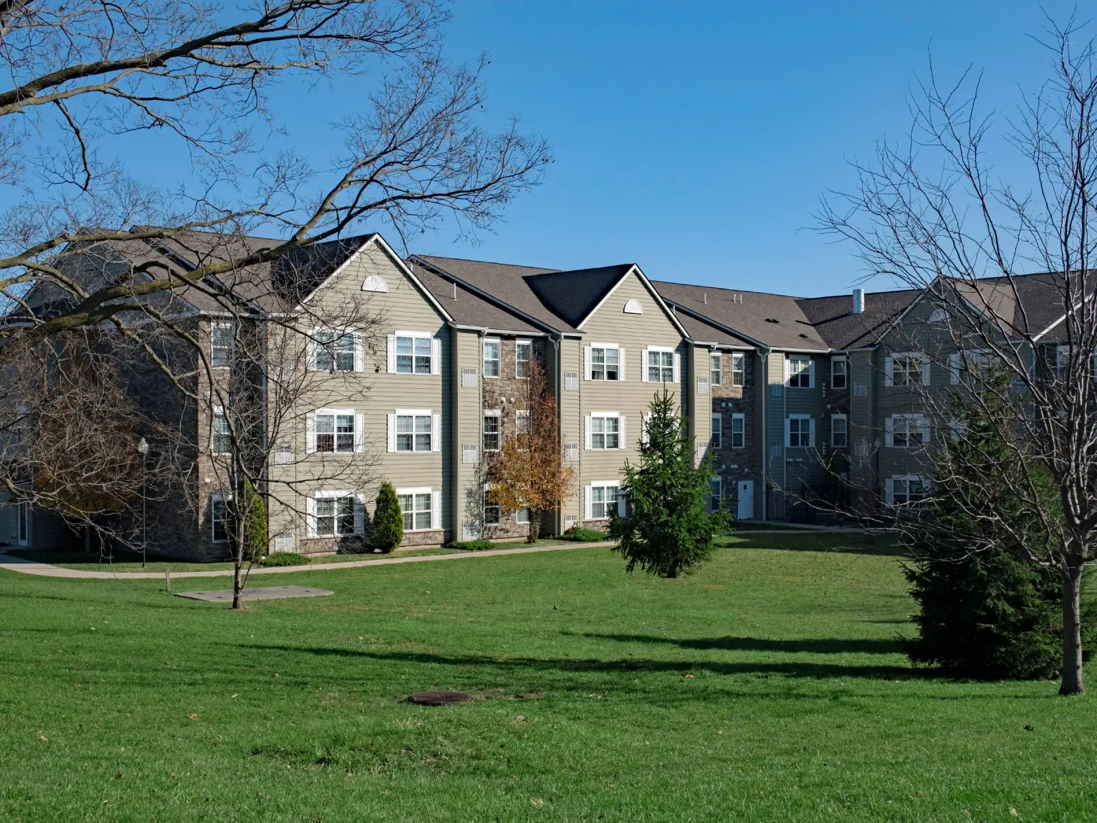 Three-story apartment buildings beside a wide, open common lawn